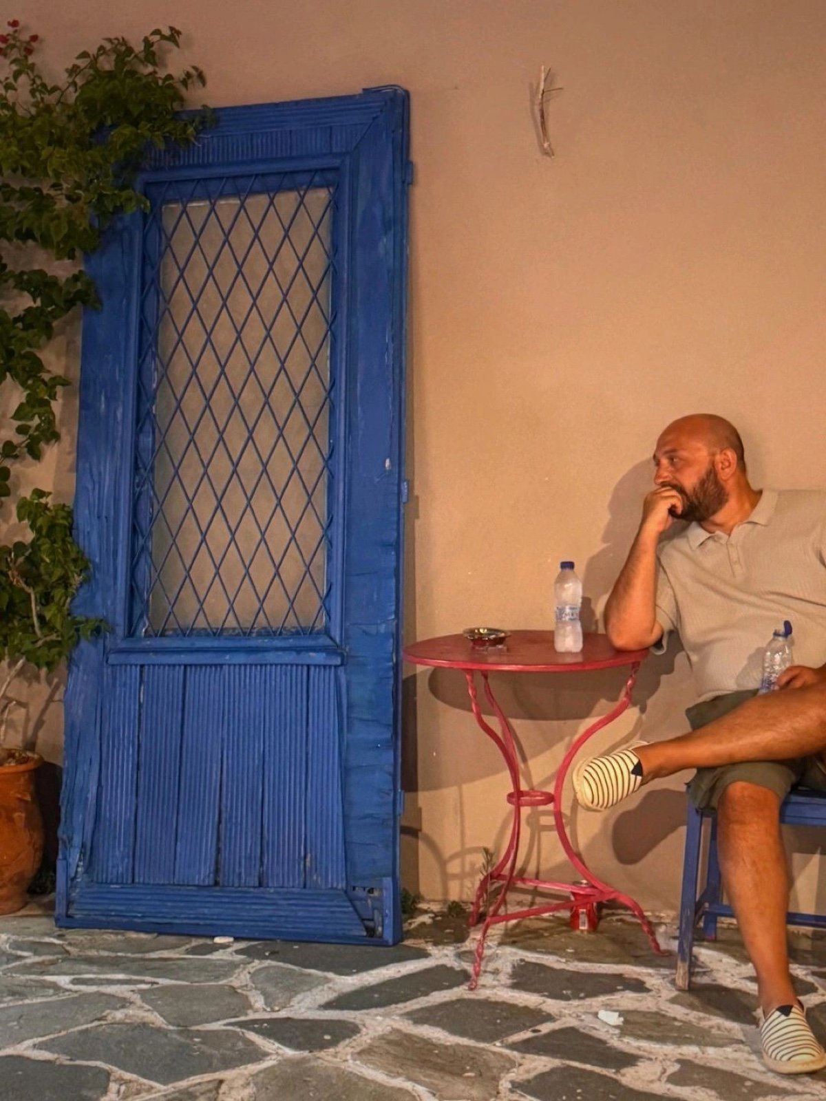 Deha Kuran sitting opposite a blue door in Greece